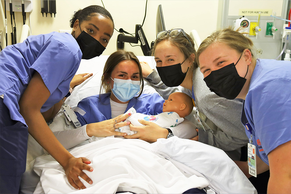 BSN class of 2023 graduates take part in a disaster drill in the sim lab in which a baby is delivered during a hurricane.
