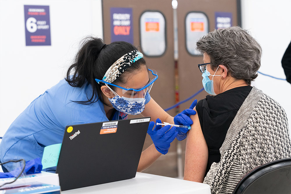 Alyssa Gail (BSN `22) vaccinates a fellow nurse against COVID 19 in the spring of 2021.