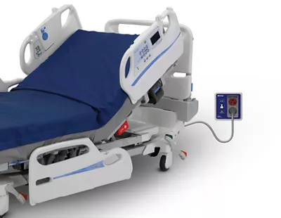 A modern, adjustable hospital bed with a blue mattress and a wired remote control for patient and caregiver use.