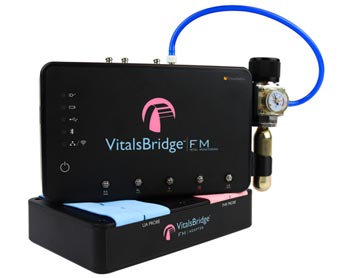 A VitalsBridge medical device with a black casing and a pink logo, with a pressure gauge attached.
