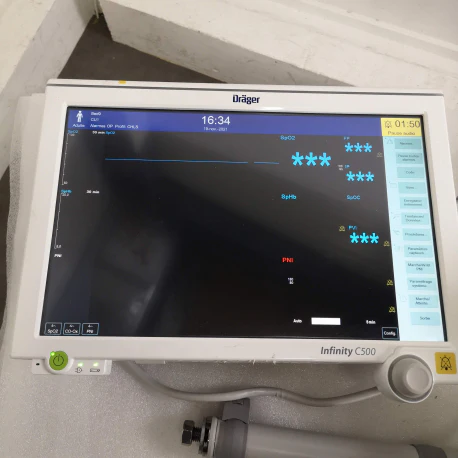 A medical monitor with a large screen displaying user interface with various icons and a large dial control.