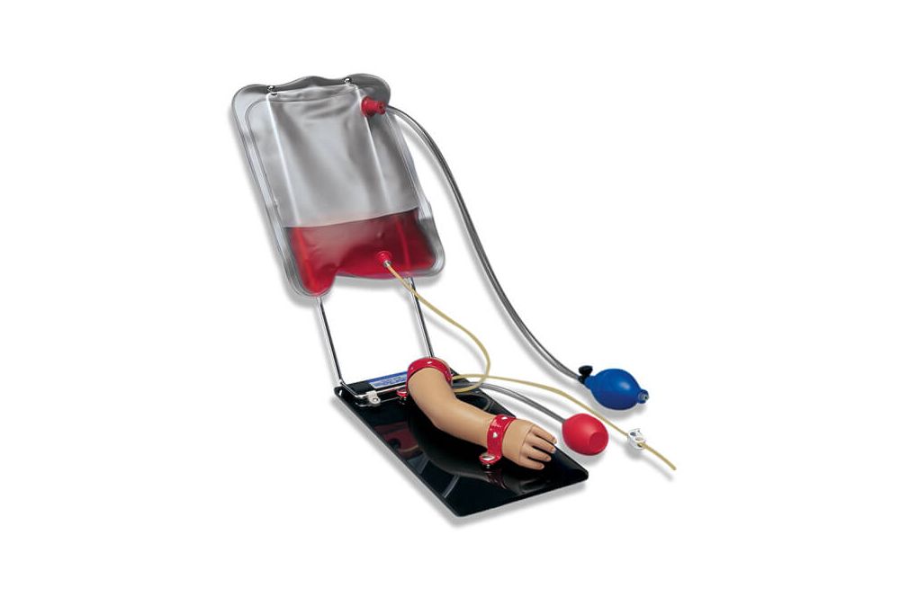 A clipboard with a mounted manikin arm, with perfusion lines attached to a bag filled with red liquid and a blue air bulb nearby